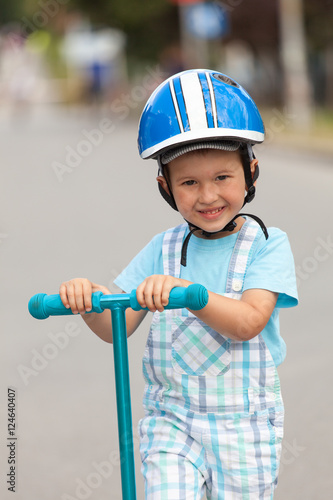 happy little boy with helmet, playing with his scooter outdoor