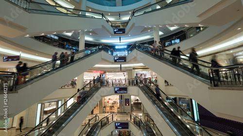 Big light multistorey shopping mall. Customers using escalators to get up and down. Trade centre of Petronas Twin Towers in Kuala Lumpur, Malaysia photo