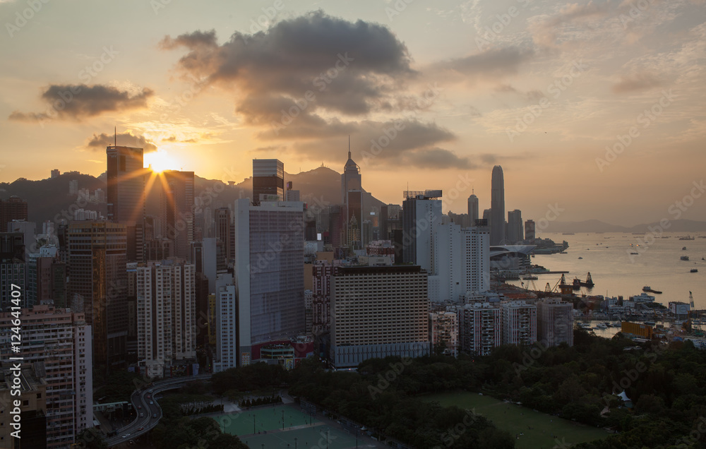 Naklejka premium Hong Kong panorama at sunset. Cityscape with high-rise buildings and water transport traffic in the harbour