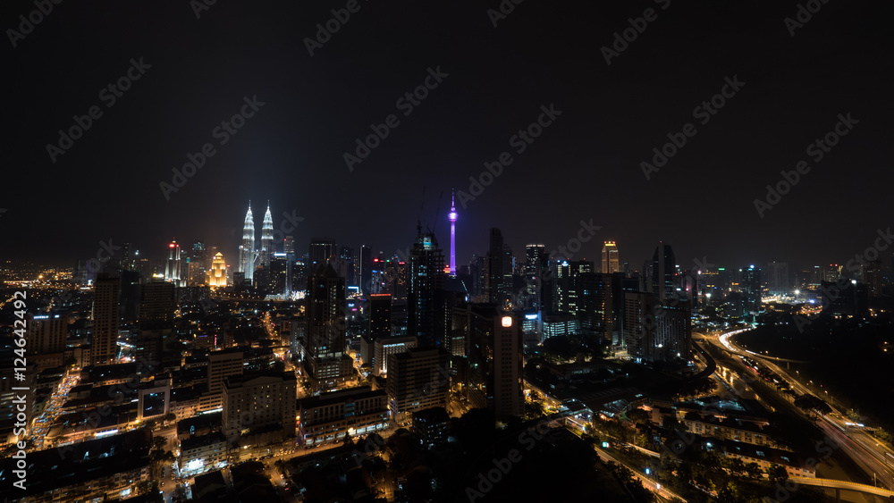 Kuala Lumpur view, Malaysia. Night city lights and transport traffic on illuminated highways. Panoramic view with Petronas Twin Towers and Menara KL Tower