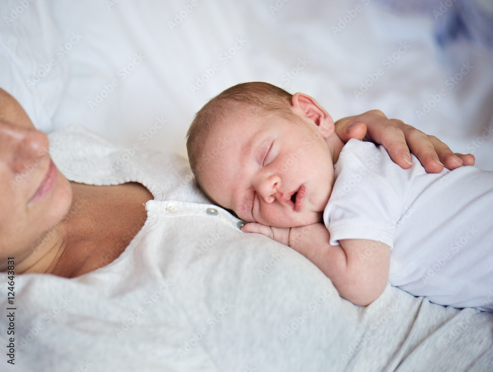 Unrecognizable mother with newborn baby son lying in bed Unrecognizable mother with newborn baby son lying in bed