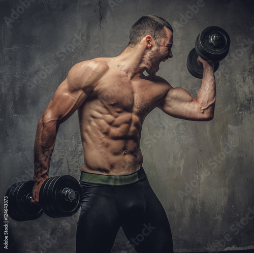Screaming, shirtless muscular male working out with dumbbells.