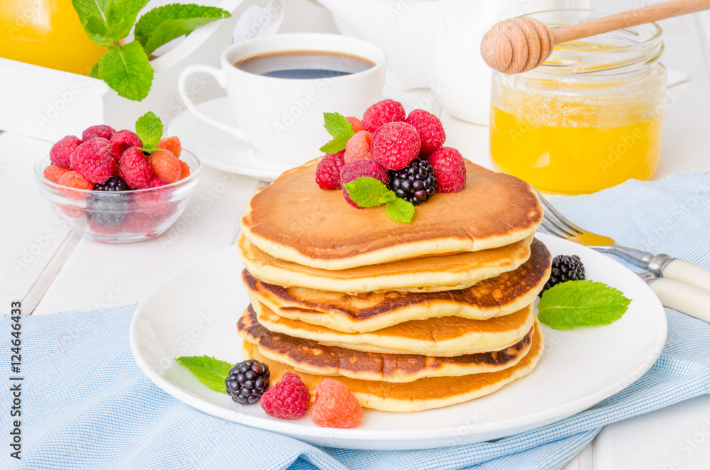 Stack of delicious american pancakes with berries on a white background