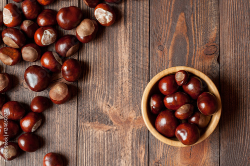 Pile of horse chestnuts on a bamboo bowl on wooden table