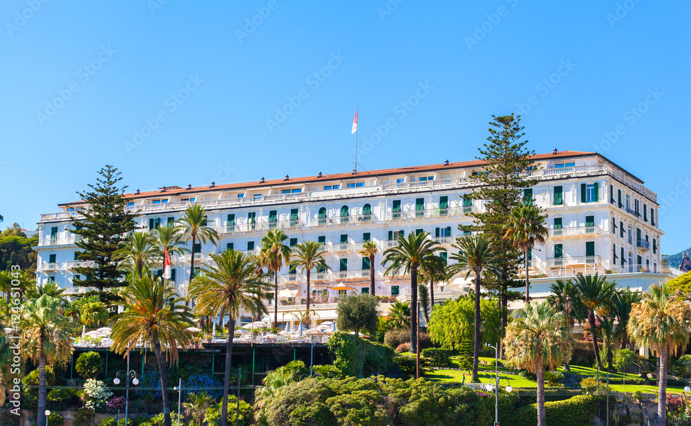 The building is famous hotel in San Remo, Italy. Beautiful historic building on the waterfront in the lush garden.