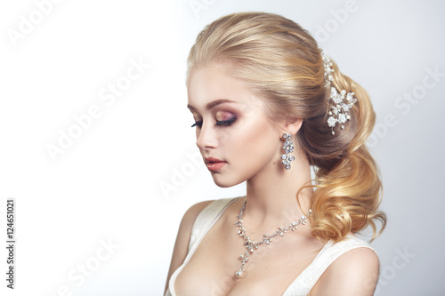 Beauty portrait of a cute blonde gorgeous bride with a beautiful hairstyle in jewelry.