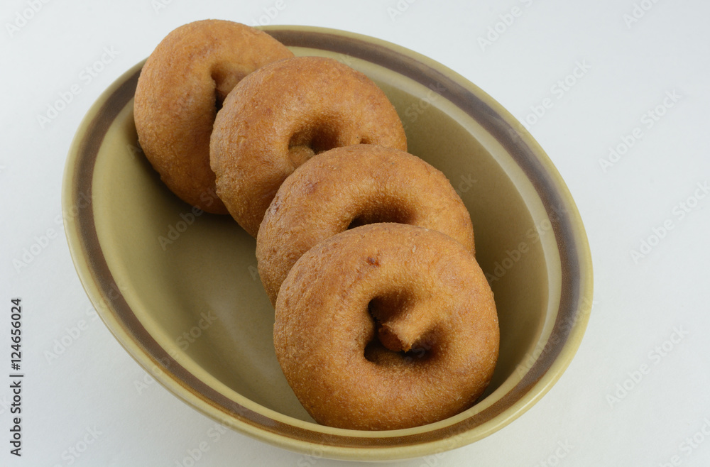 Plain breakfast donuts in brown bowl against white background Plain breakfast donuts in brown bowl against white background