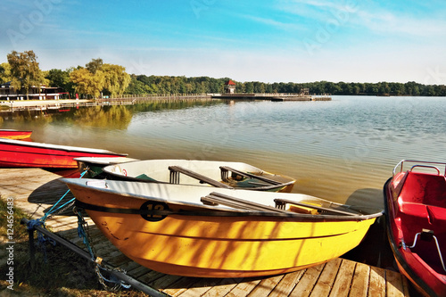 red and yellow boats and pedal boats in shore of the Alum Lake Kamencove jezero in Chomutov in the region Ustecky kraj at the end of the summer season in Czech republic photo