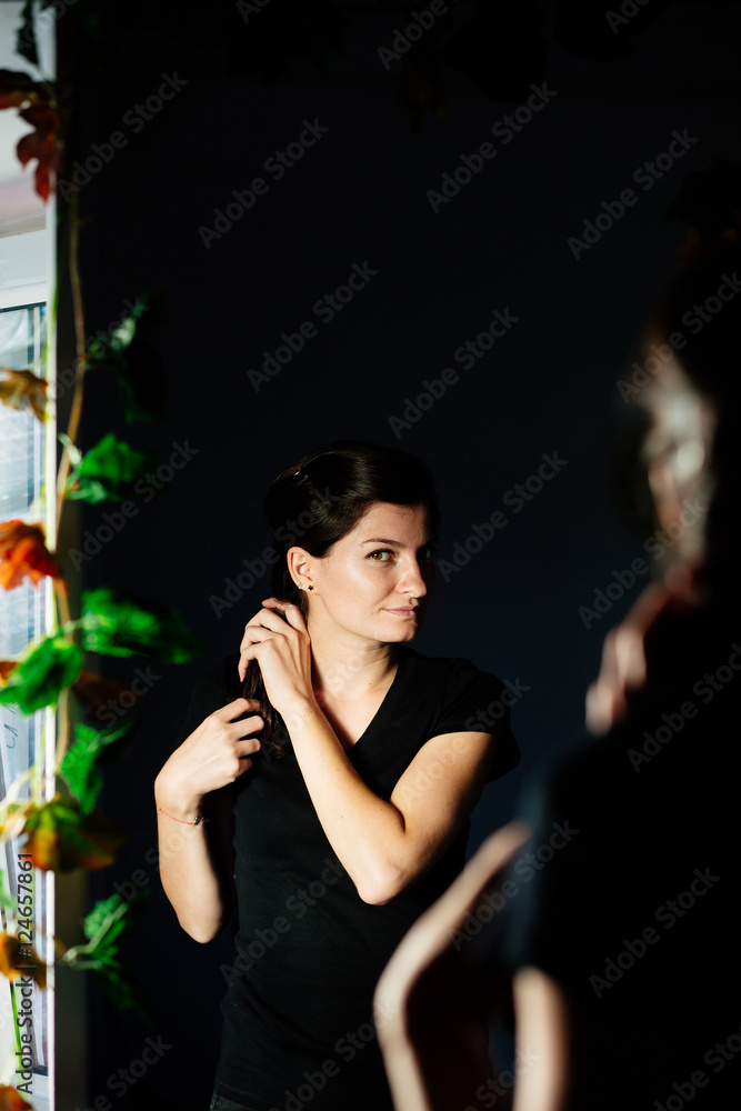 Woman arranging her hair while looking in  the mirror