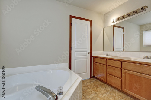 White bathroom interior with corner bathtub and vanity cabinet.