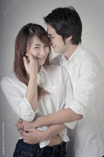 Smiling young couple embracing and standing full length on Cream background,Beautiful loving couple hugging kiss and having fun. Happy Couple in Love