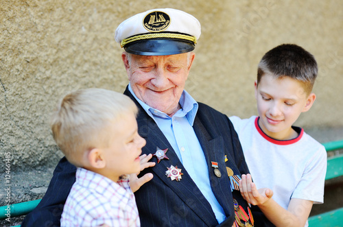 Bild auf Leinwand WWII veteran with children. Grandchildren looking at grandfather