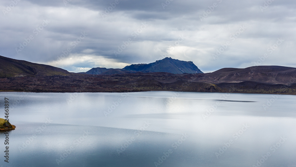 Lake with small island and sky reflection at cloudy day in Iceland