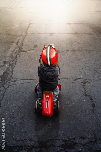 kleiner Junge auf Rutschauto im Gegenlicht 