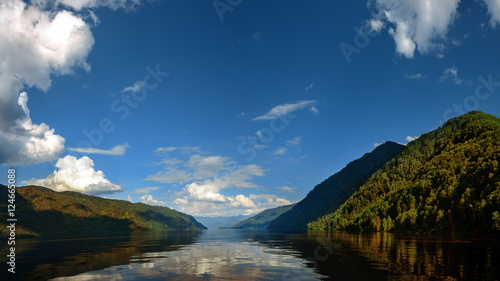 view from a boat in summer lake Teletskoye with woods on the shore between the Altai Mountains