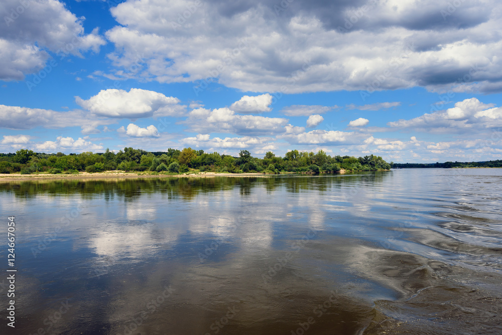 Vistula river in sunny summer day with reflections of clouds and blue sky. Poland, Europe.