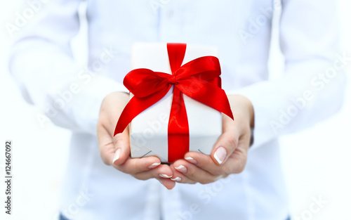 Woman's hand with a small white gift box with bow isolated on white background