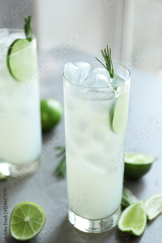 Glass of cocktail with ice on grey background