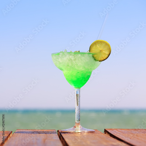 Green fairy cocktail on the wooden pier. Concept of exotic cockt photo