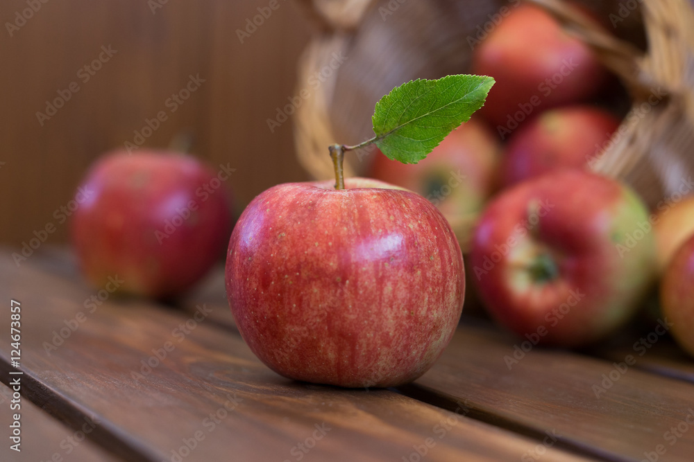 Closeup photo of whole fresh ripe juicy green apple with smooth peel and leaves on shank near basket with burlap on brown wooden table, horizontal photo Closeup photo of whole fresh ripe juicy green apple with smooth peel and leaves on shank near basket with burlap on brown wooden table, horizontal photo