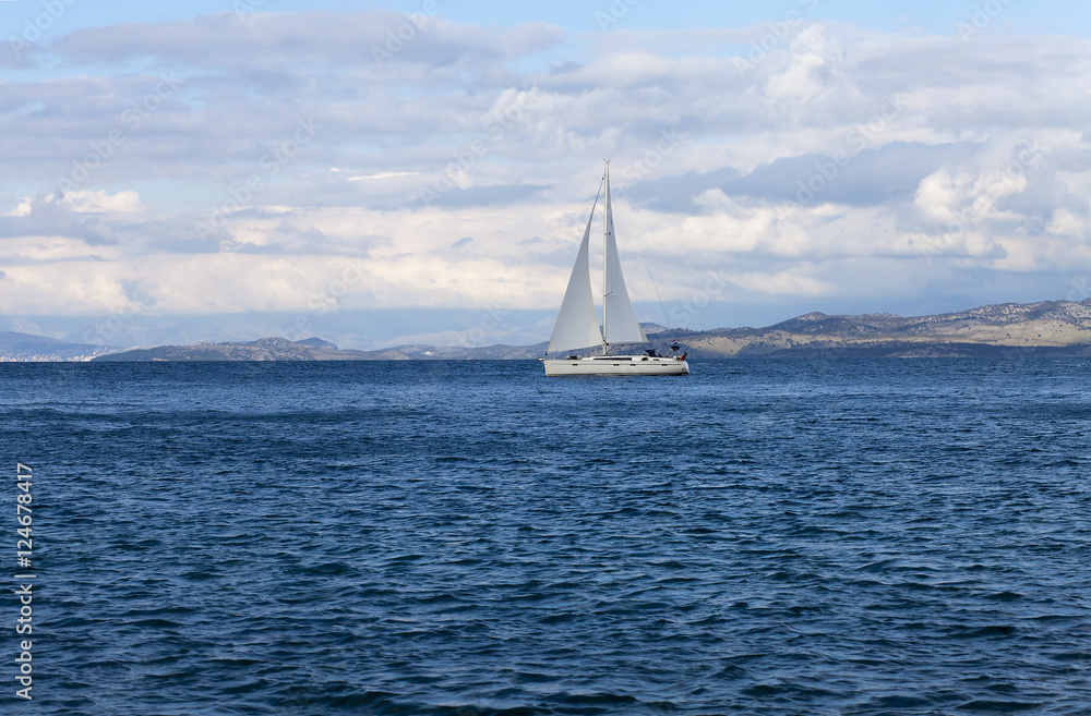 White yacht gliding through a blue bay