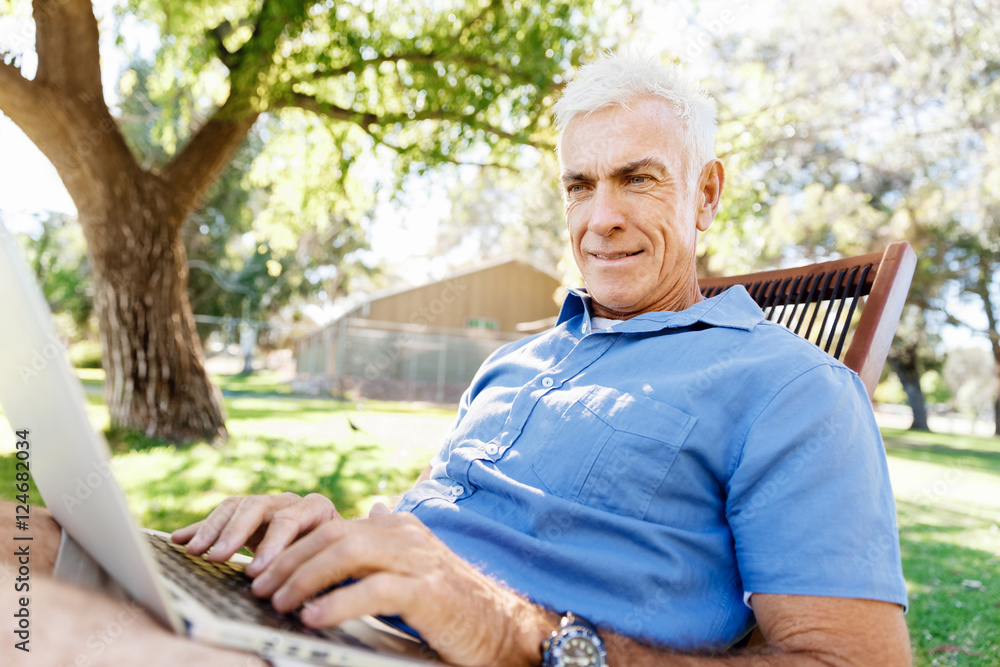 Senior man with notebook sitting in the park Senior man with notebook sitting in the park