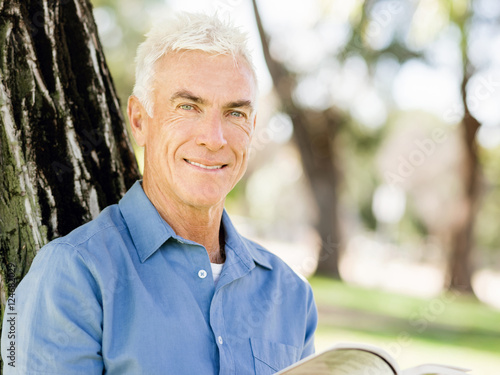 Senior man sittingin park while reading book photo