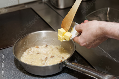 Foto Chef is putting butter to risotto