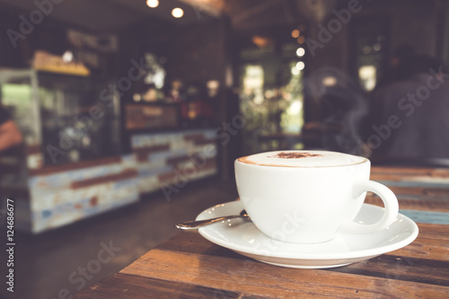 Cup of hot coffee on table in cafe with people. vintage and retro color effect - shallow depth of field