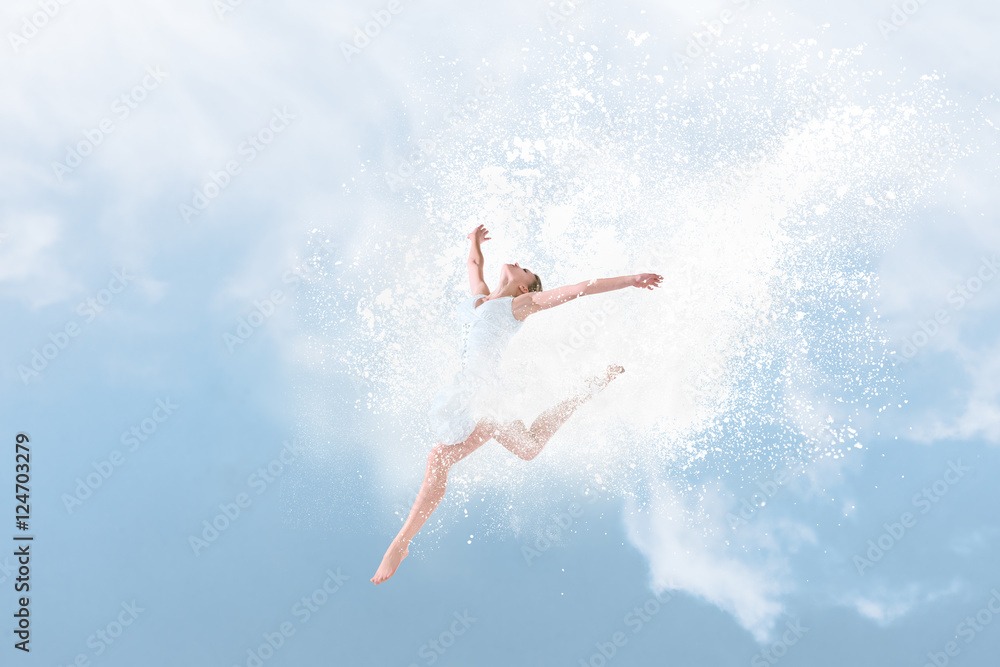 Beautiful ballet dancer jumping inside cloud of powder
