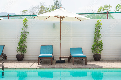 Blue sunbed with white umbrella by the pool water photo