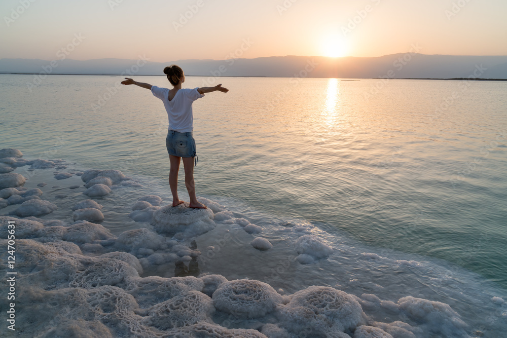Fototapeta premium Girl meets sunrise on the shore the Dead Sea in Israel