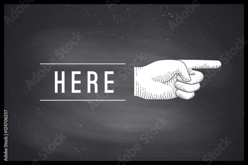 Vintage drawing of hand sign with pointing finger in engraving retro style and text Here on chalkboard. Old drawn pointing finger for sign, information sign and navigation. Vector Illustration