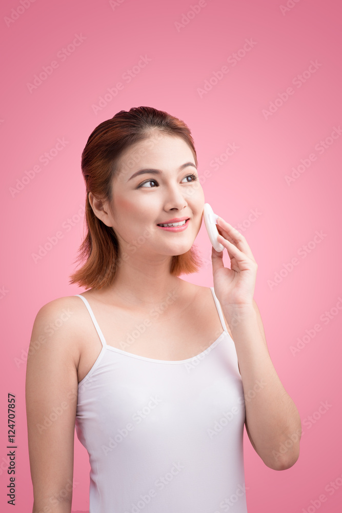 Young lady applying blusher on her face with powder puff, skin c Young lady applying blusher on her face with powder puff, skin c