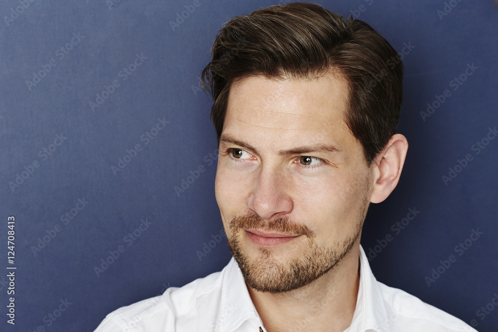Smiling man in blue studio, looking away Smiling man in blue studio, looking away