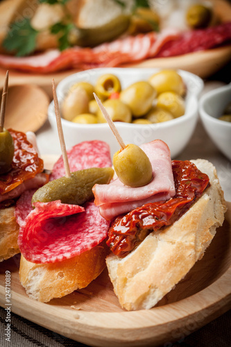 Tapas with sliced sausage, salami, olives and parsley.