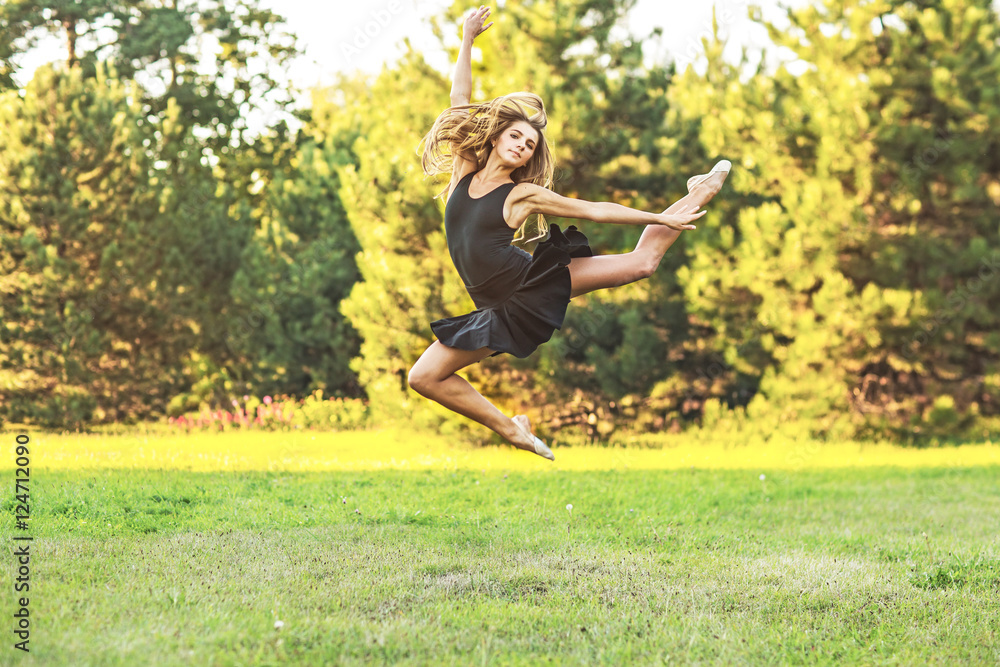 young beautiful girl flying in a jump on the nature. Girl dressed in a black dress free. Sunny autumn day