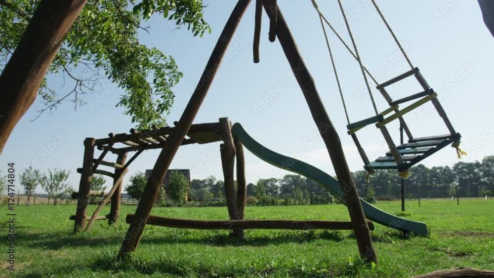 An empty wooden swing rocks back and forth on a farm in the summer. Closeup. 4k. An empty wooden swing rocks back and forth on a farm in the summer. Closeup. 4k.