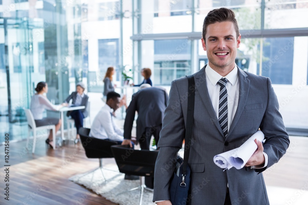 Smiling businessman standing with document in office Smiling businessman standing with document in office