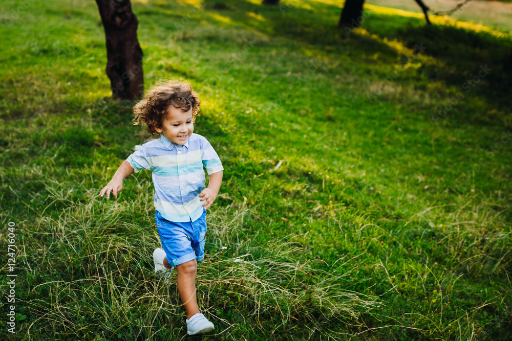 Cute little boy walking in a green park alone Cute little boy walking in a green park alone