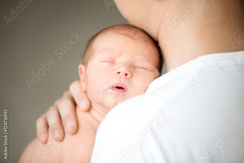 Sleeping newborn at the male shoulder, hold gently by a hand. Family, healthy birth concept photo, close up