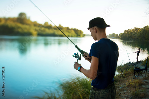 Teenage boy fishing on a fishing tackle in the river in summer