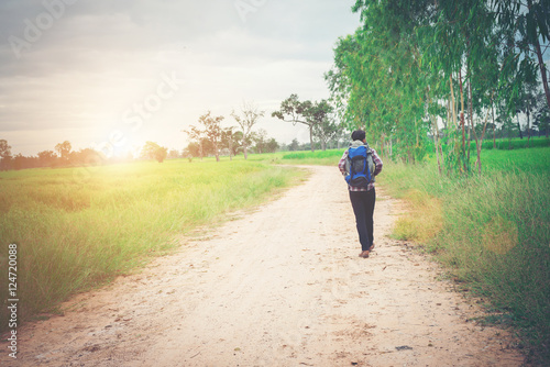 Back of young hipster man with backpack on his shoulder walking