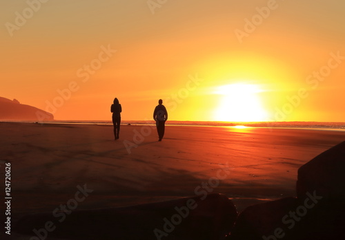 two people walking into sunset at beach
