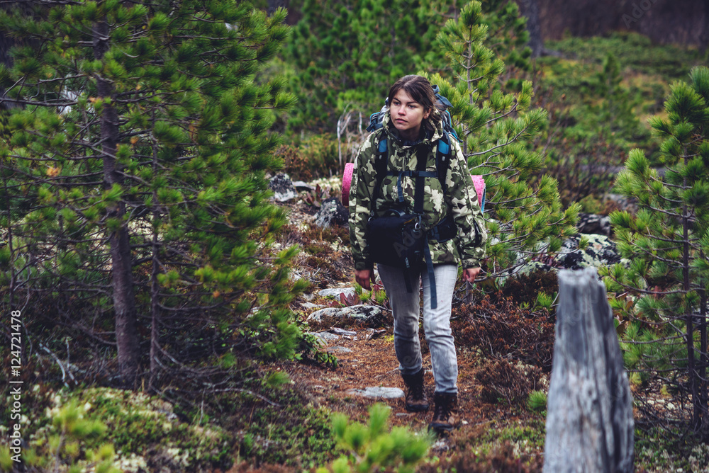 girl with a backpack going up in the mountain forest