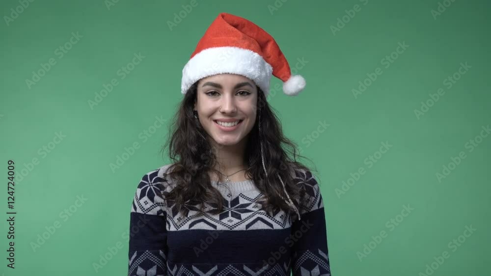 Young brunette woman in a red santa's cap smiling, chroma key green screen background Young brunette woman in a red santa's cap smiling, chroma key green screen background