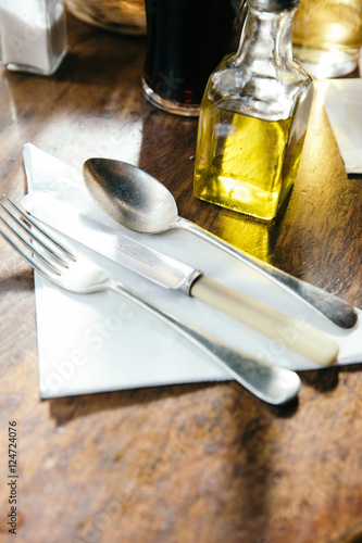 Cutlery set at wooden dinner table with oil dressing. photo