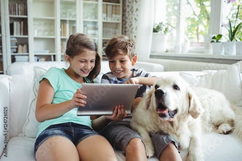 Children using digital tablet while sitting on a sofa