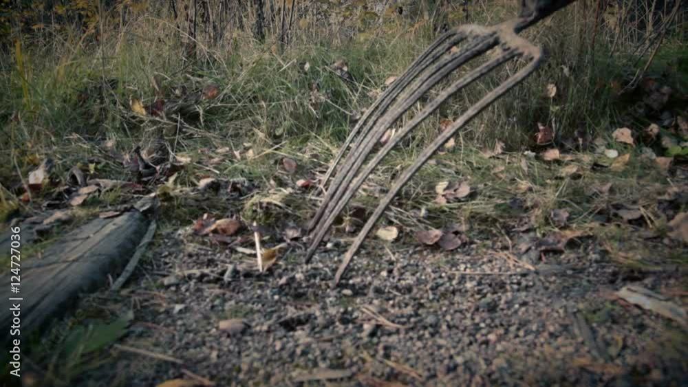 someone with pitchfork goes along old railway