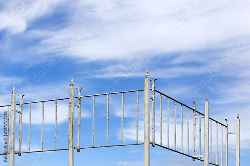 Vintage metal fence and a blue cloudy sky